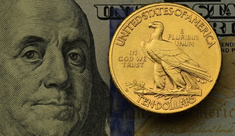 one american gold coin at top of a dollar bill