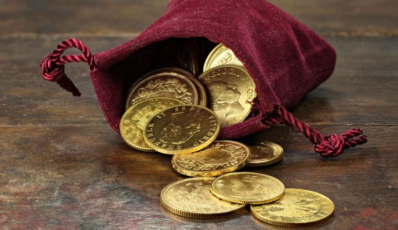 various gold coins in a velvet ourse on rustic wooden background