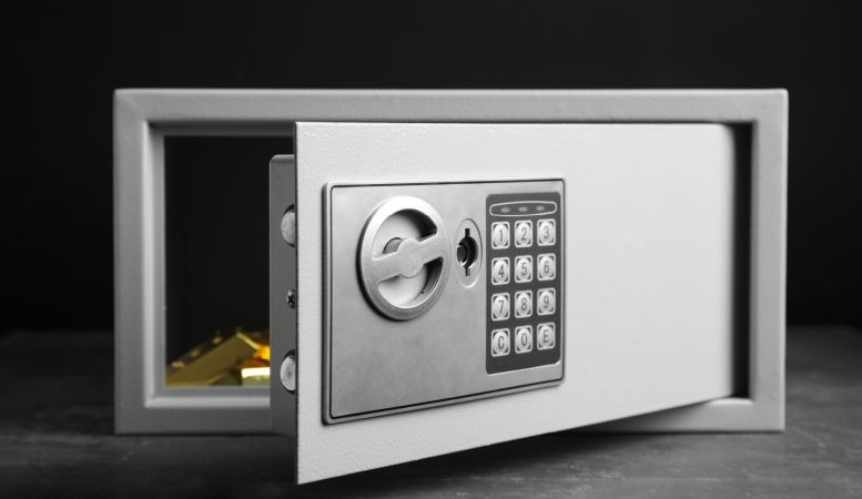 open steel safe with gold bars on grey table