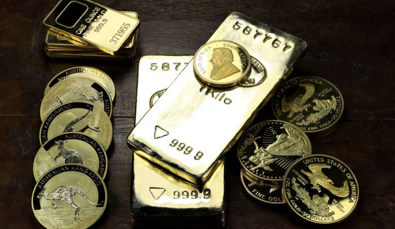 various gold bars and gold coins on wooden table
