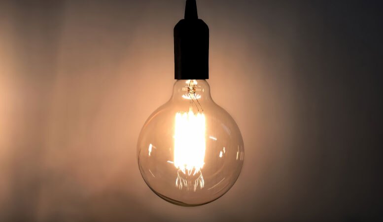 open incandescent light bulb on dark room