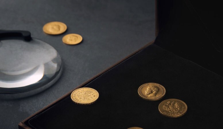 numismatic gold and copper coins with magnifying glass