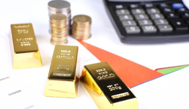gold bullion with coins and calculator as background