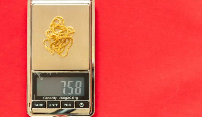 gold necklace weigh on digital electronic scale on red background