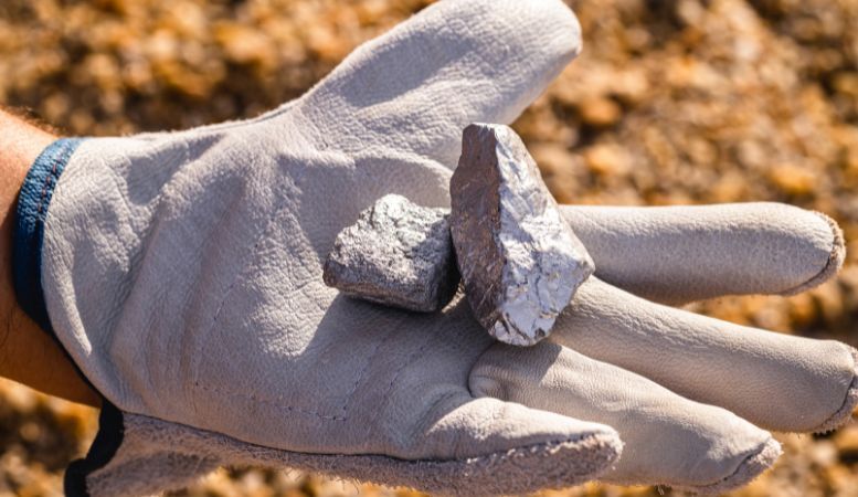 hand holding silver stone in mining site