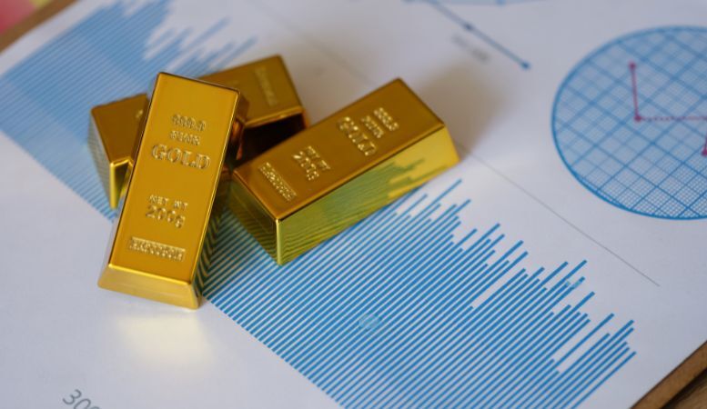 small gold ingots on financial statistics document with charts