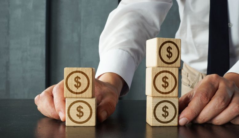 investor moving stack of wooden blocks with dollar sign