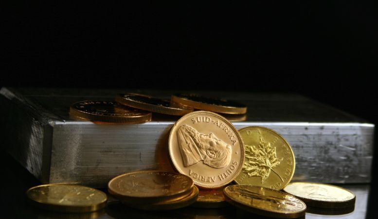 different types of gold coins and silver bar on dark background