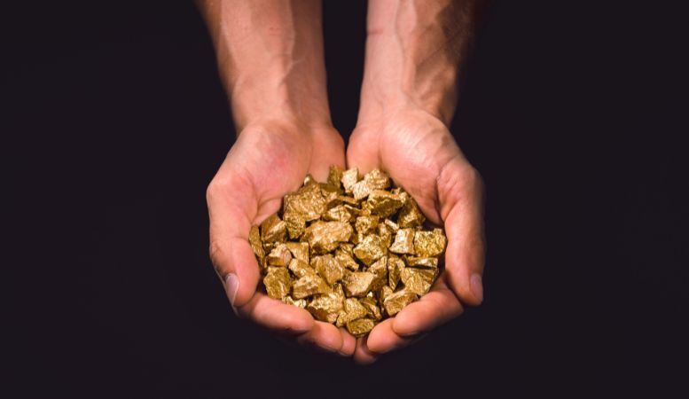 hand of man full of gold nuggets