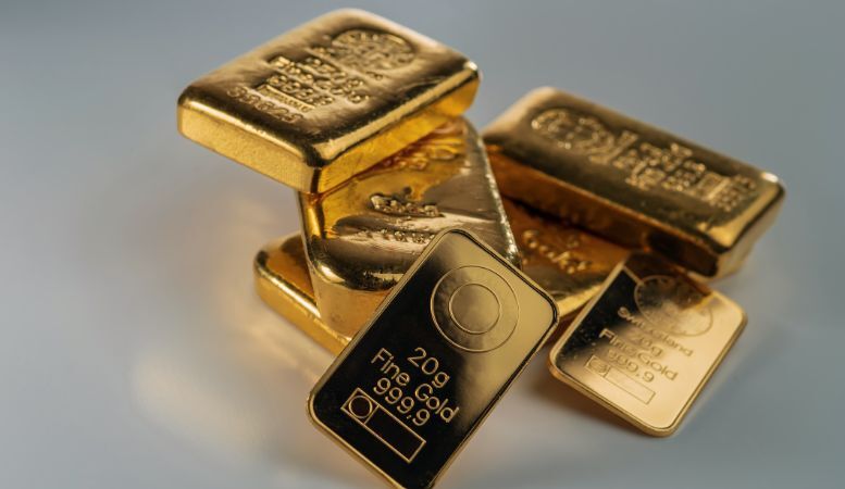 several gold bars of different weights on grey background