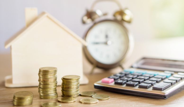 stack of coins calculator small house on blurred clock background