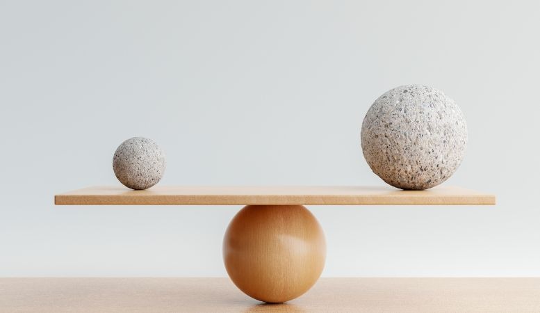 wooden balancing scale with one big rock and one small rock