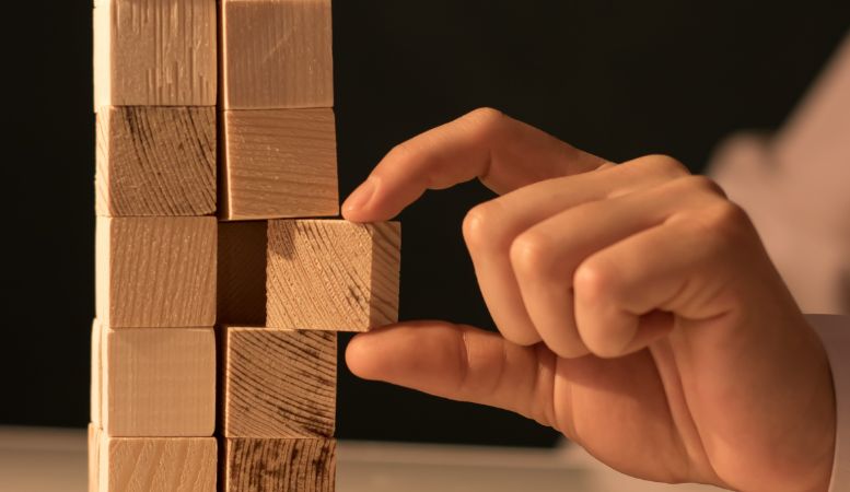 man pulling piece of cube on stack of wooden cubes