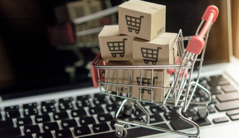 small shopping cart with paper cartons on top of laptop