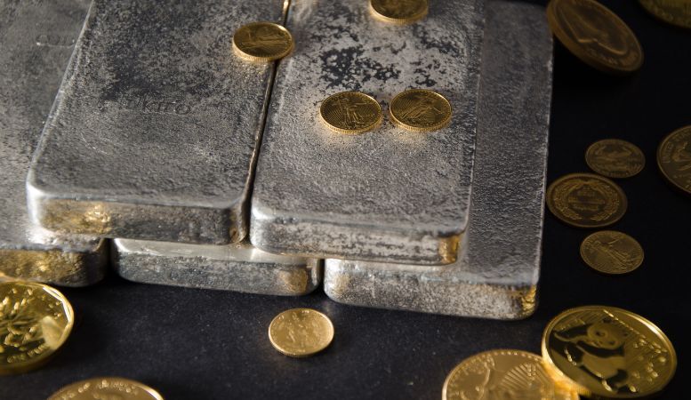 silver bars with gold coins on black background